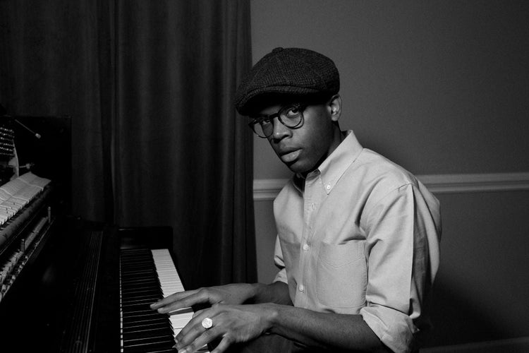 Black and white photo of Sean Mason in a cap playing piano